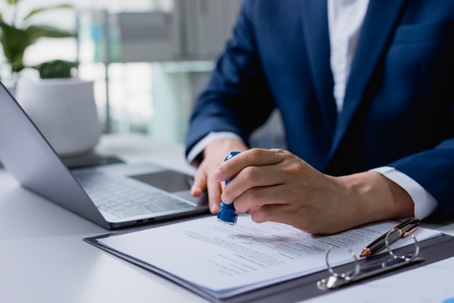 Business contract document stamping with approval seal, agreement verification, official paperwork process